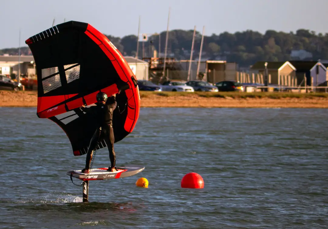 a man on a surfboard holding a sail