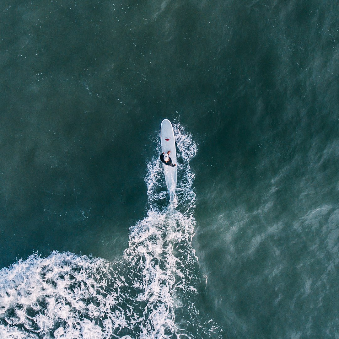 Aerial surfer shot by Hydrofoiling person surfing under sunny sky