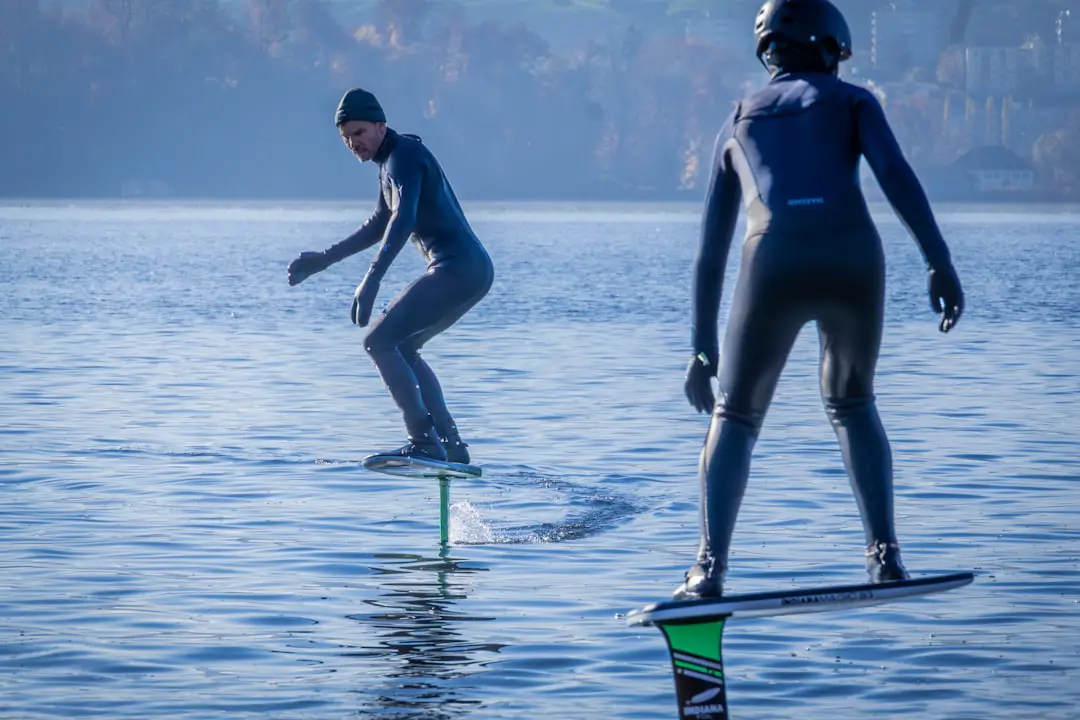 A couple of people riding surfboards on a body of water