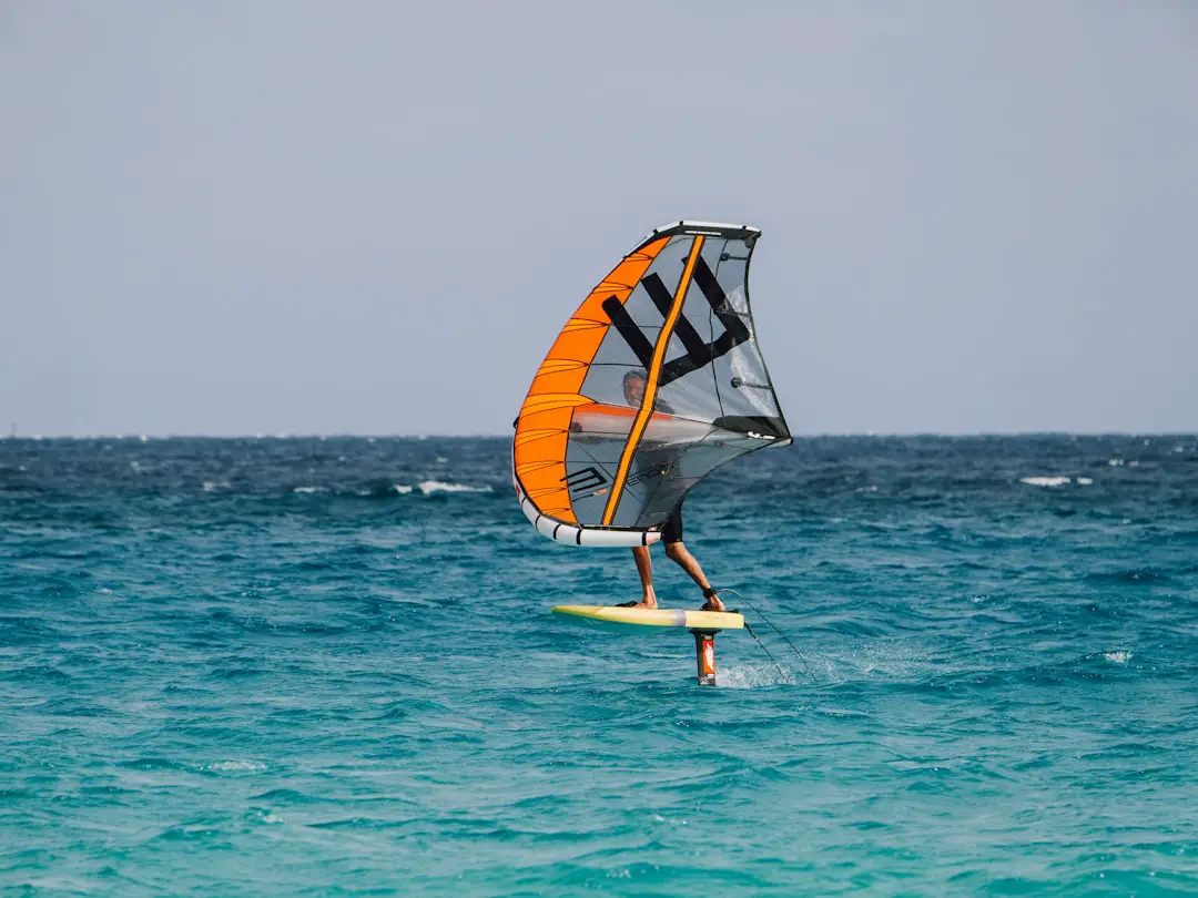 What is the difference between hydrofoil windsurfing and regular windsurfing? by Hydrofoiling A person windsurfing in the ocean on a sunny day