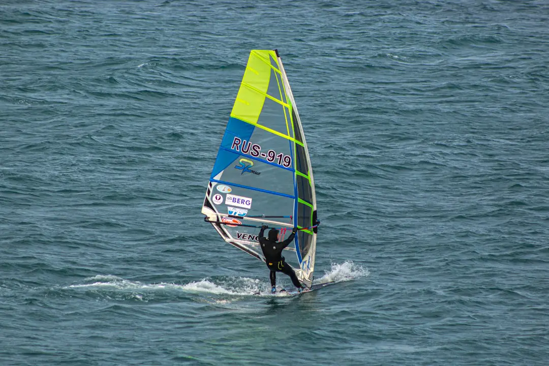 A man riding a sailboat on top of a body of water