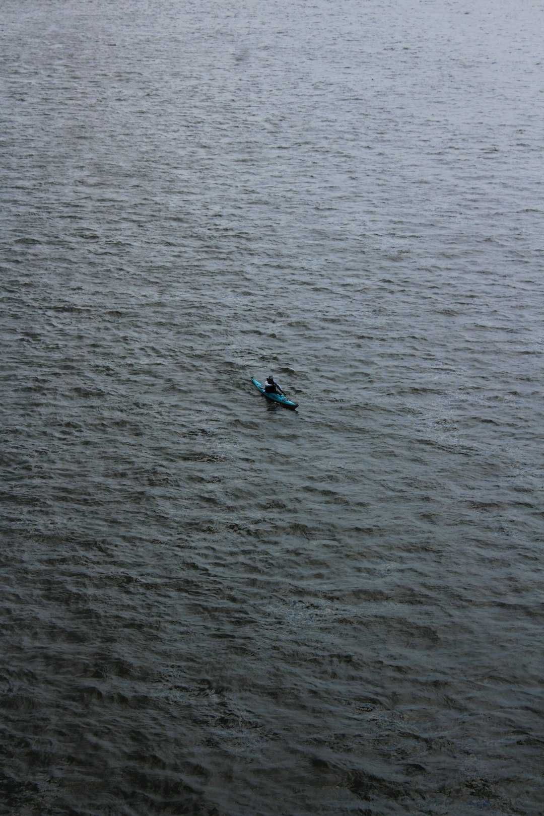 Kayaker paddles alone on the vast, dark water.